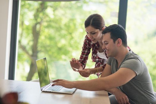 happy young couple buying online using laptop a computer and a credit card in their luxury home villa