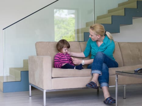 young mother and cute little girl enjoying their free time hugging on the sofa in their luxury home villa