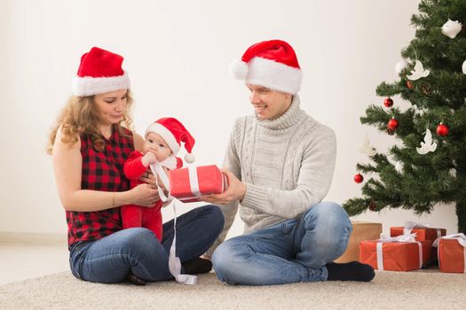 Happy couple with baby celebrating Christmas together at home