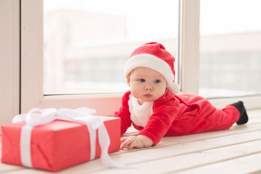 Beautiful little baby celebrates Christmas. New Year's holidays. Baby in a Christmas costume and in santa hat.