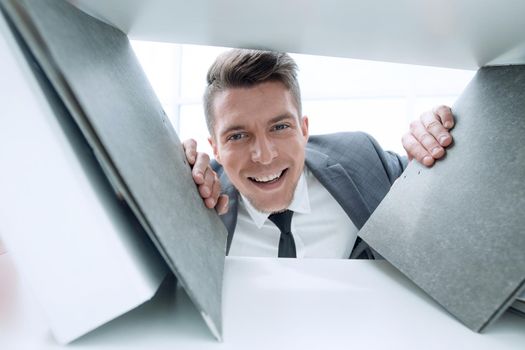 businessman in the background smiling and holding documents that stand on a shelf in a cabinet