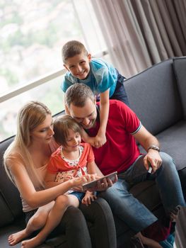 Happy Young Family Playing Together with tablet at home sitting on the sofa