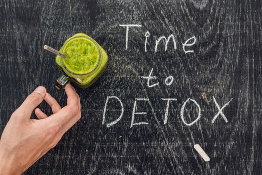 TIME TO DETOX chalk inscription on the wooden table and Green smoothies made of spinach. Healthy eating and sports concept.