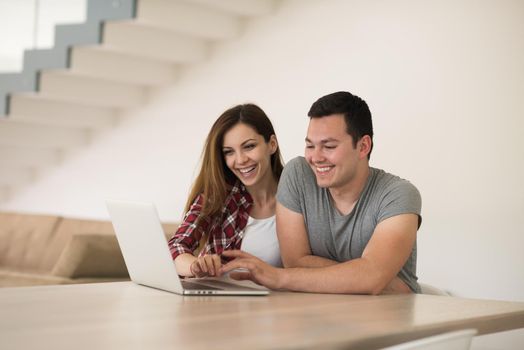 happy young couple buying online using laptop a computer and a credit card in their luxury home villa