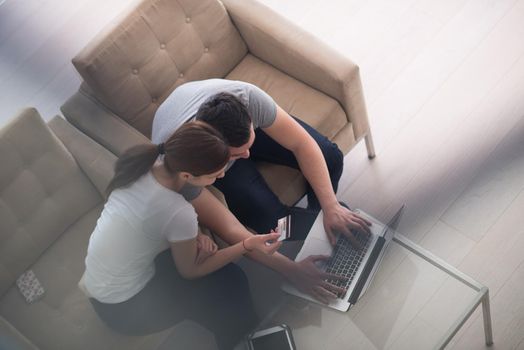 happy young couple buying online using laptop a computer and a credit card in their luxury home villa