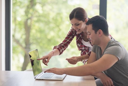 happy young couple buying online using laptop a computer and a credit card in their luxury home villa