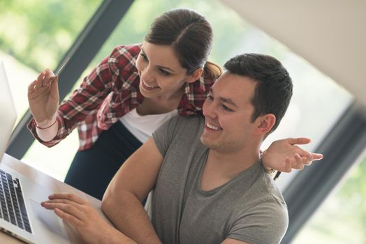 happy young couple buying online using laptop a computer and a credit card in their luxury home villa