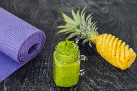 Green smoothies made of spinach and pineapple and a yoga mat. Healthy eating and sports concept.