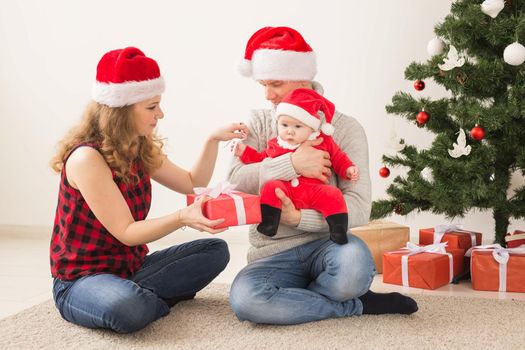 Holidays, children and family concept - Happy couple with baby celebrating Christmas together at home