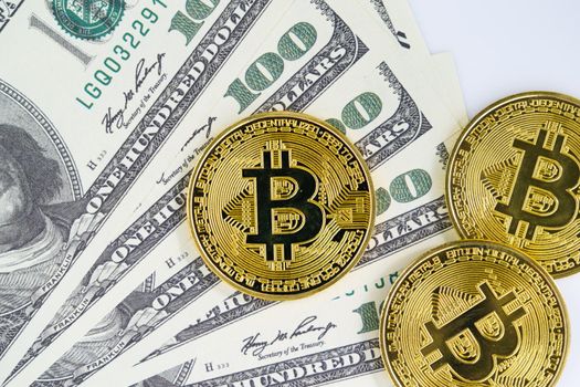 Bitcoins coin and banknotes of one hundred dollars. Close up of metal shiny bitcoin crypto currency coins and US dollar