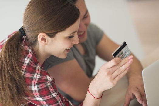 happy young couple buying online using laptop a computer and a credit card in their luxury home villa