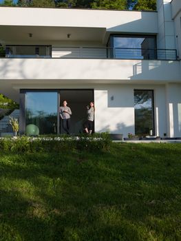 young beautiful handsome couple enjoying morning coffee on the door of their luxury home villa