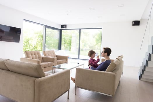 young mother and cute little girl enjoying their free time hugging on the sofa in their luxury home villa