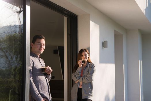 young beautiful handsome couple enjoying morning coffee on the door of their luxury home villa