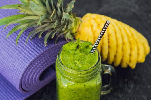 Green smoothies made of spinach and pineapple and a yoga mat. Healthy eating and sports concept.