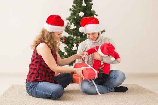 Holidays, children and family concept - Happy couple with baby celebrating Christmas together at home