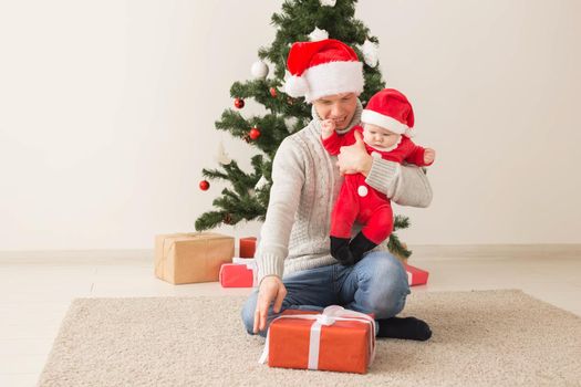 Father with his baby boy wearing Santa hats celebrating Christmas