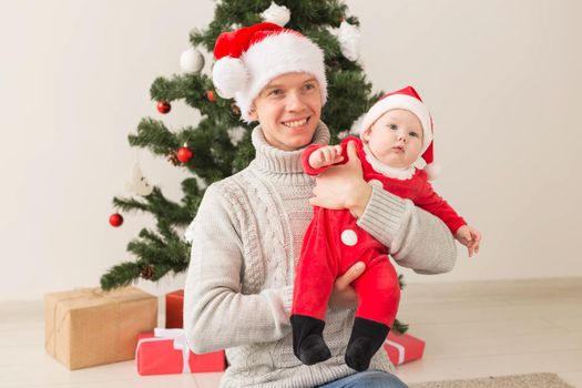 Father with his baby boy wearing Santa hats celebrating Christmas