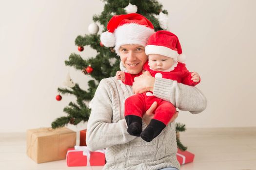 Father with his baby boy wearing Santa hats celebrating Christmas