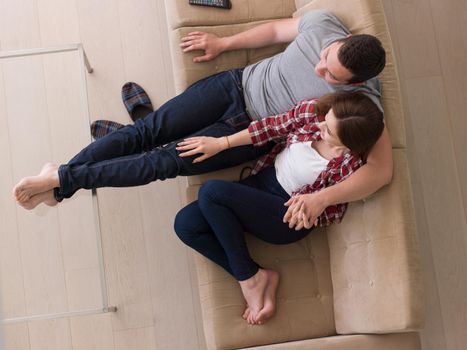 Young couple on the sofa watching television together in their luxury home