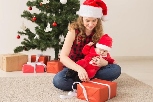 Family, childhood and Christmas concept - Portrait of happy mother and adorable baby in suit of Santa.