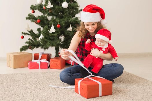 Family, childhood and Christmas concept - Portrait of happy mother and adorable baby in suit of Santa.