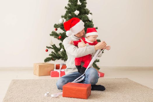 Father with his baby boy wearing Santa hats celebrating Christmas