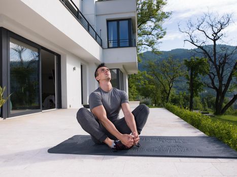 young handsome man doing morning yoga exercises in front of his luxury home villa