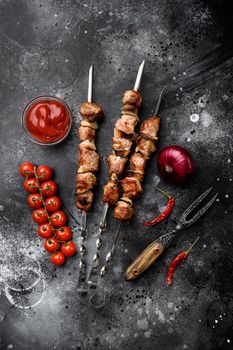 Tasty marinated meat skewers set, on black dark stone table background, top view flat lay, with copy space for text