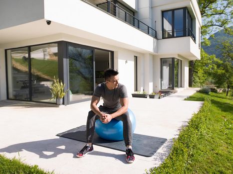 young handsome man doing morning yoga exercises in front of his luxury home villa