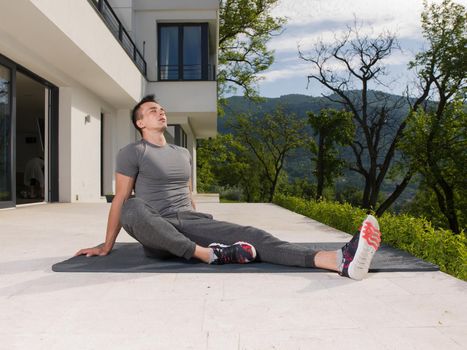 young handsome man doing morning yoga exercises in front of his luxury home villa