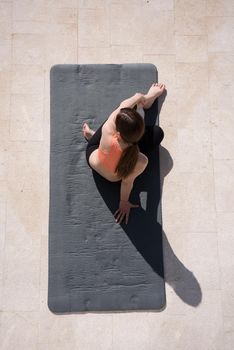 young handsome woman doing morning yoga exercises in front of her luxury home villa top view