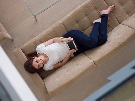 young happy woman on sofa using tablet computer at luxury home