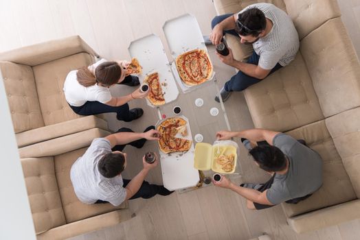 a group of young people cheerfully spending time while eating pizza in their luxury home villa