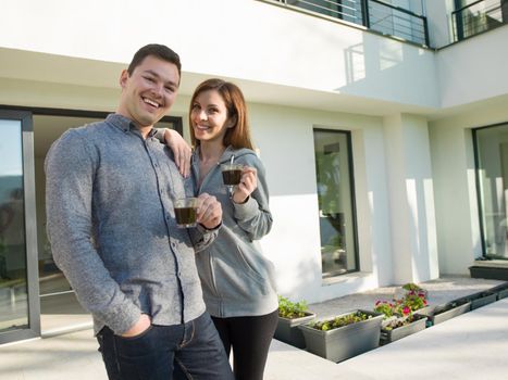 young beautiful handsome couple enjoying morning coffee in front of their luxury home villa