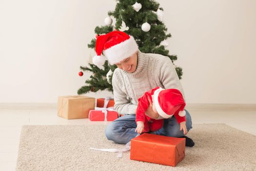 Father with his baby boy wearing Santa hats celebrating Christmas