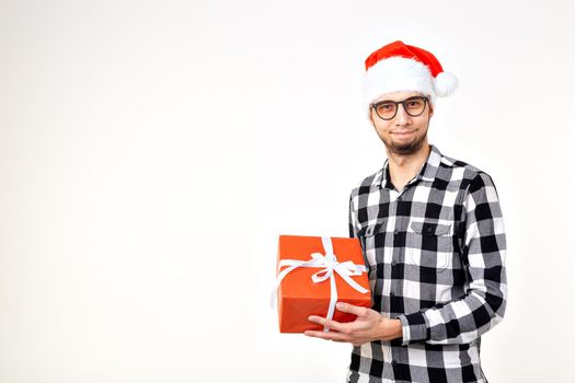 Holidays and presents concept - Funny man in Christmas hat holding gift box on white background.