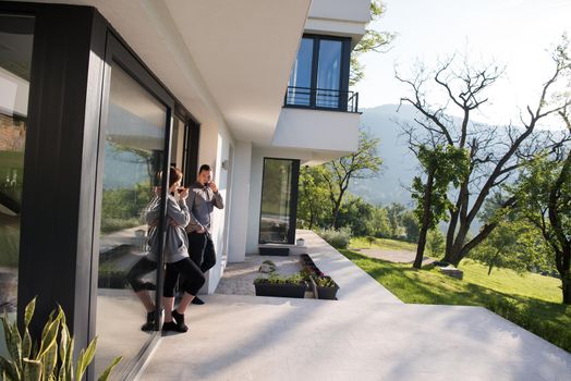 young beautiful handsome couple enjoying morning coffee on the door of their luxury home villa