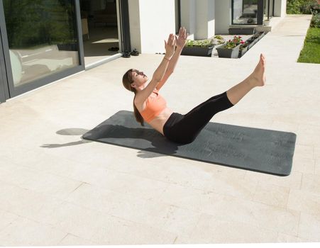 young handsome woman doing morning yoga exercises in front of her luxury home villa