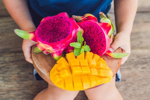 Diced dragon fruit and mango in the hands of the boy.