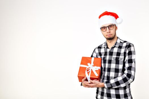 Holidays and presents concept - Funny man in Christmas hat holding gift box on white background.