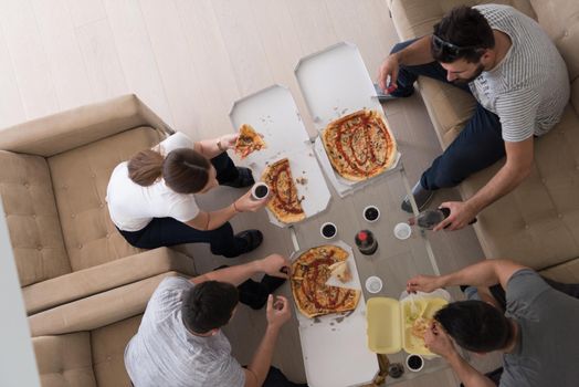 a group of young people cheerfully spending time while eating pizza in their luxury home villa