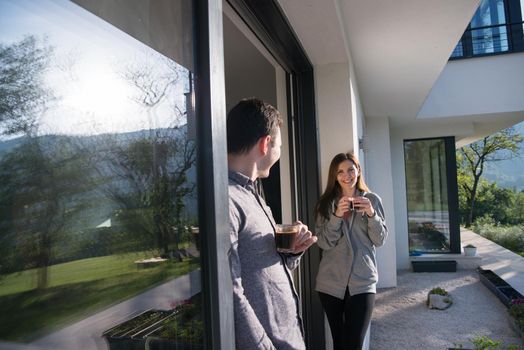 young beautiful handsome couple enjoying morning coffee on the door of their luxury home villa