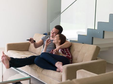 Young couple on the sofa watching television together in their luxury home