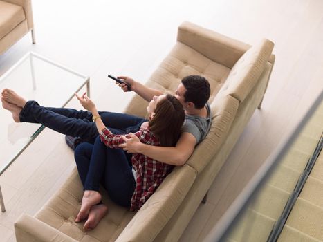 Young couple on the sofa watching television together in their luxury home