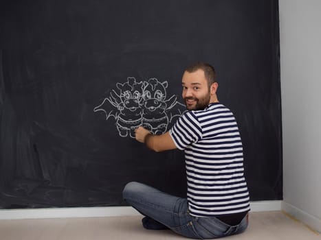 Conceptual photo of future dad drawing his imaginations about the future life with children on chalk board