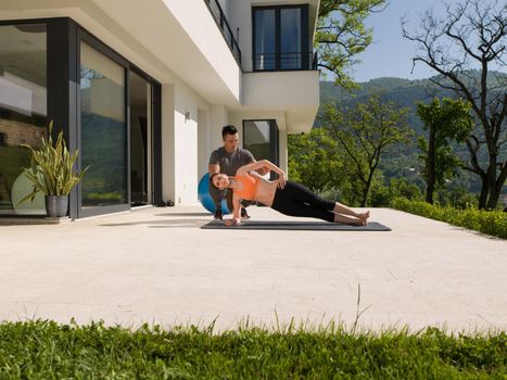 young handsome woman with personal trainer doing morning yoga exercises in front of her luxury home villa