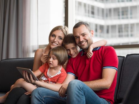 Happy Young Family Playing Together with tablet at home sitting on the sofa