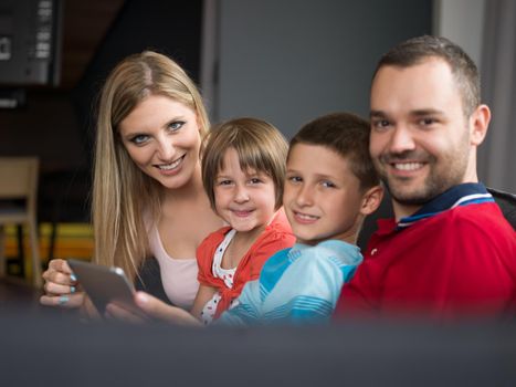 Happy Young Family Playing Together with tablet at home sitting on the sofa