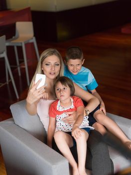 Happy family siting on sofa and using cell phone for video call  at home